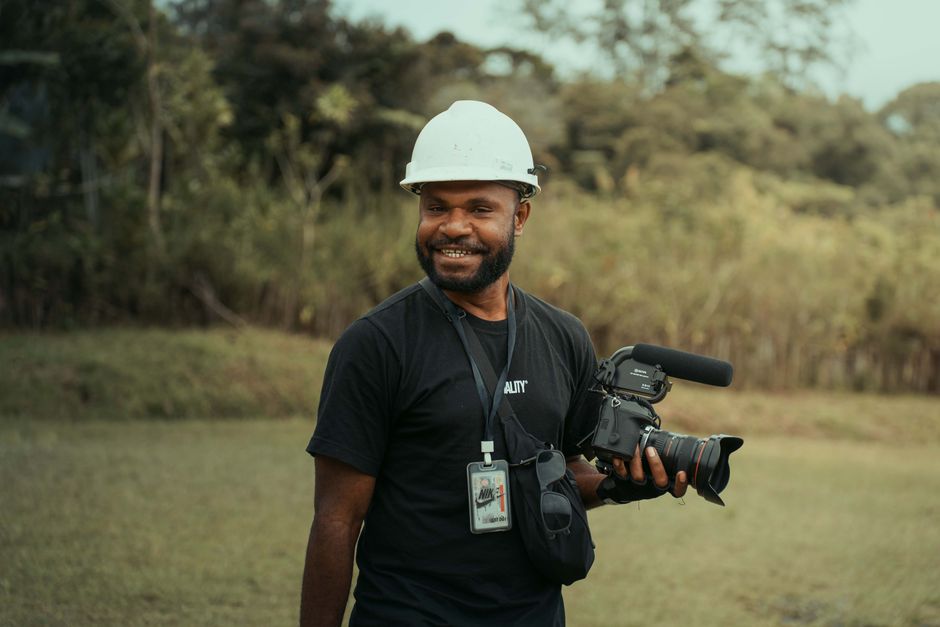 A smiling wedding videographer holding professional camera gear.
